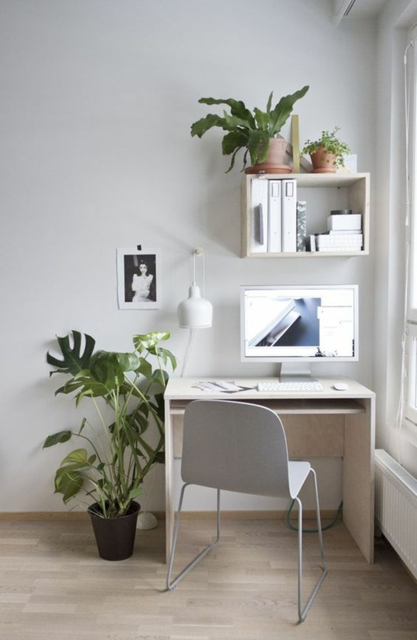 Et minimalistisk hjemmekontor i skandinavisk stil med hvitt skrivebord og grønne planter.